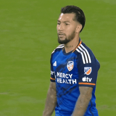 A Man In A Blue Mercy Health Jersey Stands On A Field GIF