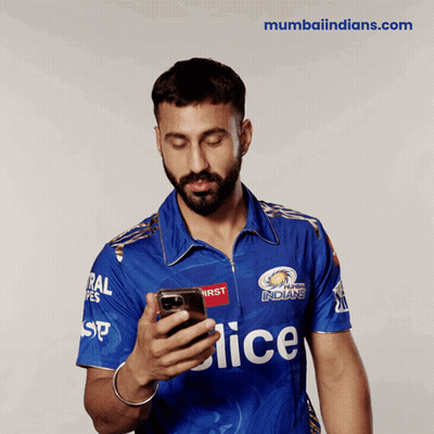 A Man In A Blue Mumbai Indians Jersey Looks At His Cell Phone GIF