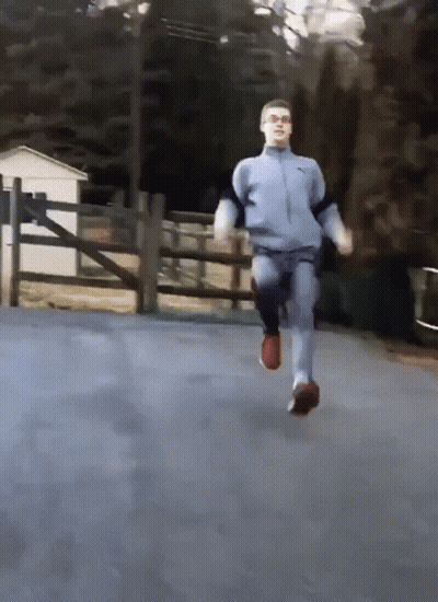 A Man In A Blue Nike Jacket Is Running On A Road GIF