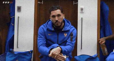 A Man In A Blue Nike Jacket Sits In A Changing Room GIF