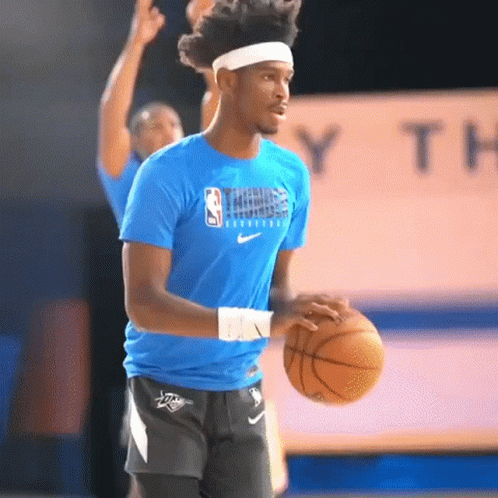 A Man In A Blue Nike Shirt Is Holding A Basketball GIF