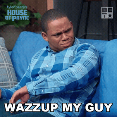 A Man In A Blue Plaid Shirt Is Sitting On A Blue Couch With The Words Wazzup My Guy Above Him GIF