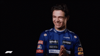A Man In A Blue Racing Uniform Is Smiling And Clapping His Hands . GIF