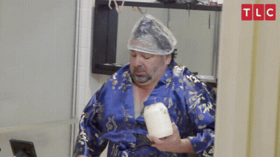 A Man In A Blue Robe Is Holding A Container Of Milk GIF