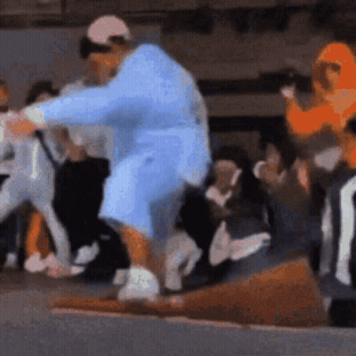 A Man In A Blue Robe Is Standing In Front Of A Crowd Of People . GIF