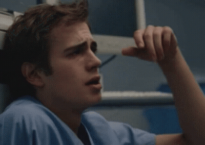 A Man In A Blue Scrub Top Is Holding His Head GIF