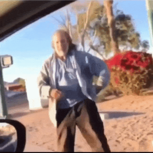 A Man In A Blue Shirt And Black Pants Is Dancing In A Car . GIF