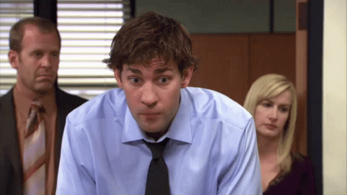 A Man In A Blue Shirt And Black Tie Looks At The Camera GIF