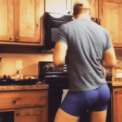 A Man In A Blue Shirt And Blue Shorts Is Standing In A Kitchen Cooking . GIF