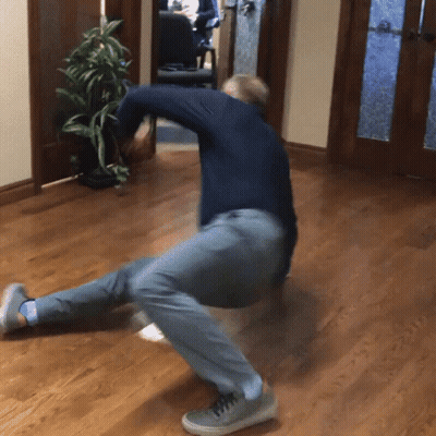A Man In A Blue Shirt And Grey Pants Is Kneeling Down On The Floor GIF