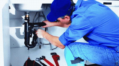 A Man In A Blue Shirt And Hat Is Working On A Pipe Under A Sink GIF