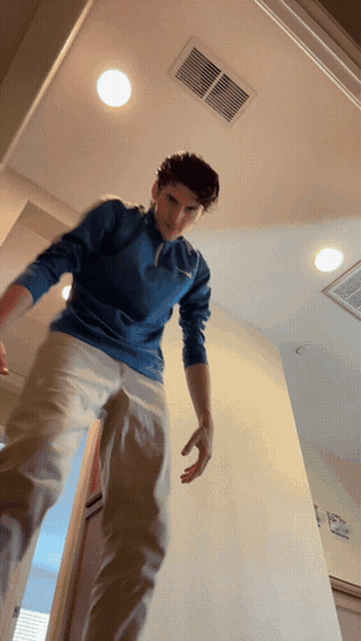 A Man In A Blue Shirt And Khaki Pants Is Standing In A Doorway GIF