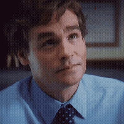 A Man In A Blue Shirt And Polka Dot Tie Looks To The Side GIF