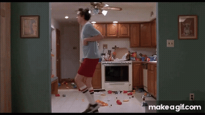 A Man In A Blue Shirt And Red Shorts Is Jumping In A Kitchen . GIF
