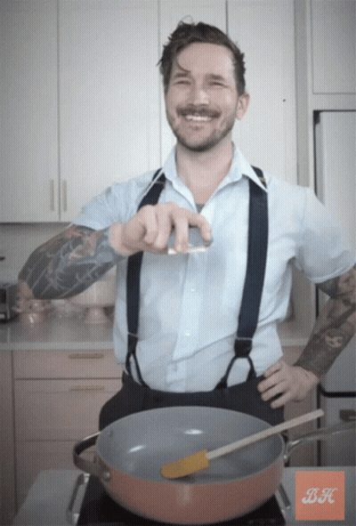 A Man In A Blue Shirt And Suspenders Is Standing In Front Of A Pot With A Spatula In It GIF