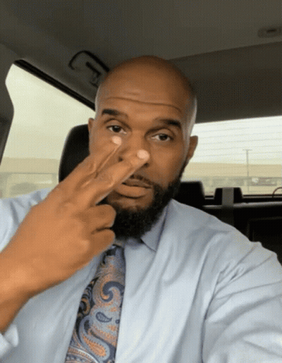 A Man In A Blue Shirt And Tie Holds His Finger Up To His Nose GIF