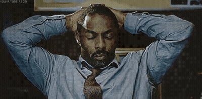 A Man In A Blue Shirt And Tie Holds His Hands To His Head GIF