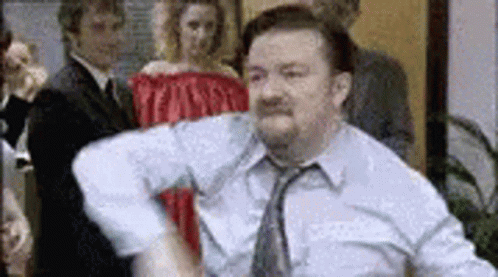 A Man In A Blue Shirt And Tie Is Dancing In Front Of A Group Of People . GIF