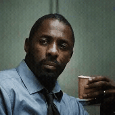 A Man In A Blue Shirt And Tie Is Holding A Cup Of Coffee In His Hand . GIF