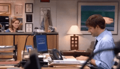 A Man In A Blue Shirt And Tie Is Sitting At A Desk In An Office . GIF