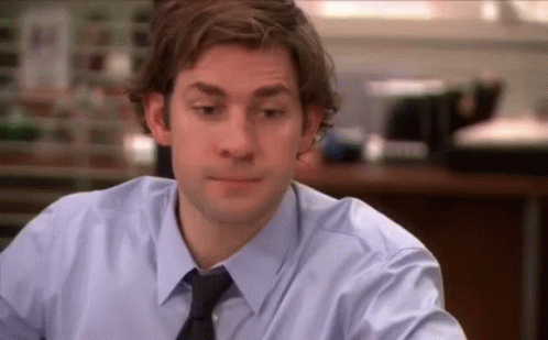 A Man In A Blue Shirt And Tie Is Sitting At A Table In An Office . GIF