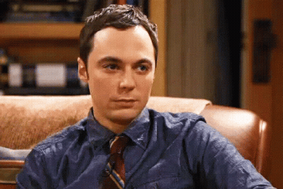 A Man In A Blue Shirt And Tie Is Sitting In A Chair And Making A Funny Face . GIF