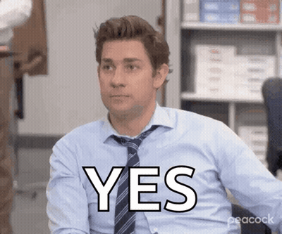 A Man In A Blue Shirt And Tie Is Sitting In An Office And Says Yes GIF