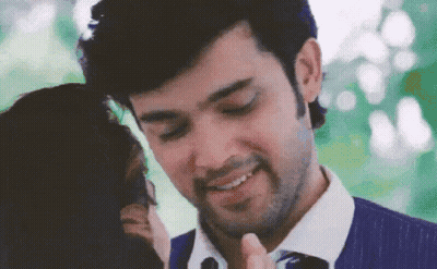 A Man In A Blue Shirt And Tie Is Smiling While A Woman Looks On . GIF