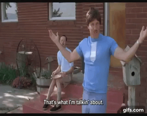A Man In A Blue Shirt And Tie Is Standing In Front Of A Brick House Talking To Another Man . GIF