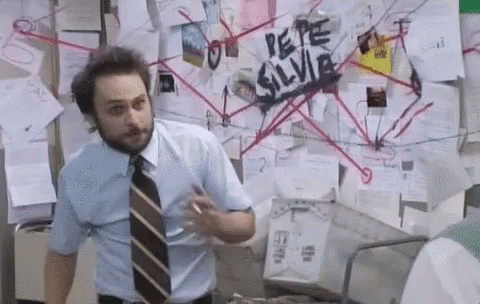 A Man In A Blue Shirt And Tie Is Standing In Front Of A Bulletin Board With Papers On It . GIF