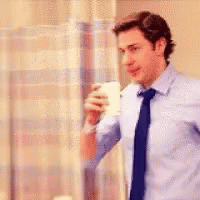 A Man In A Blue Shirt And Tie Is Standing In Front Of A Window Holding A Cup . GIF
