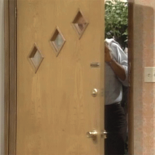 Man In Blue Shirt And Tie In Front Of Wooden Door GIF