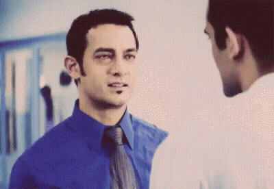 A Man In A Blue Shirt And Tie Is Talking To Another Man GIF