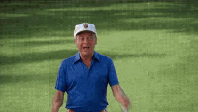 A Man In A Blue Shirt And White Hat Is Holding A Golf Club On A Golf Course GIF