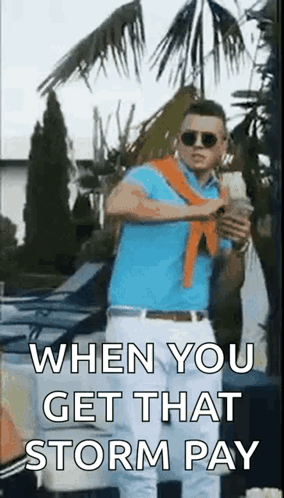 A Man In A Blue Shirt And White Pants Is Standing In Front Of A Palm Tree Holding A Bottle Of Beer . GIF