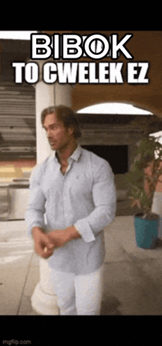 A Man In A Blue Shirt And White Pants Is Standing In Front Of A Sign That Says Bibok To Cwelek Ez . GIF