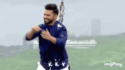 A Man In A Blue Shirt And White Shorts Is Dancing In A Field GIF