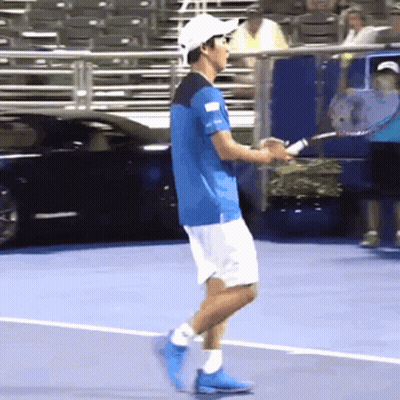 A Man In A Blue Shirt And White Shorts Is Holding A Tennis Racket GIF