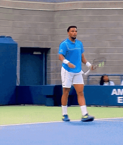 A Man In A Blue Shirt And White Shorts Is Holding A Tennis Racquet GIF