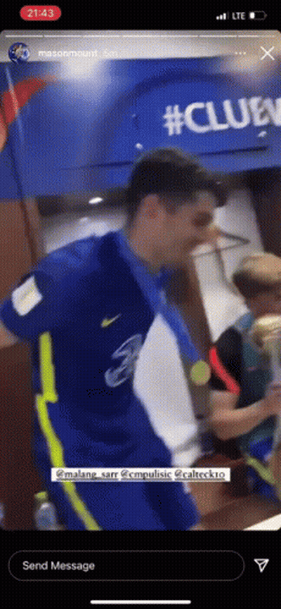A Man In A Blue Shirt And Yellow Pants Is Holding A Medal Around His Neck . GIF