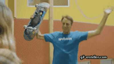 A Man In A Blue Shirt Holding A Skateboard With Gif-Erstellen.com Written On The Bottom GIF