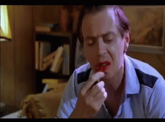 A Man In A Blue Shirt Is Applying Red Lipstick On His Lips GIF
