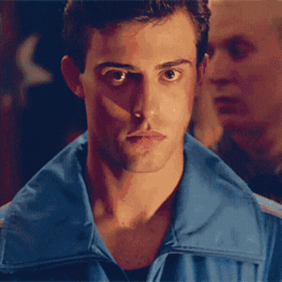 A Man In A Blue Shirt Is Covering His Face With His Hand GIF