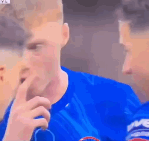 A Man In A Blue Shirt Is Covering His Mouth With His Hand While Another Man Looks On . GIF