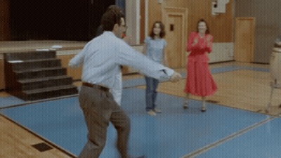 A Man In A Blue Shirt Is Dancing In A Gym With Two Women GIF