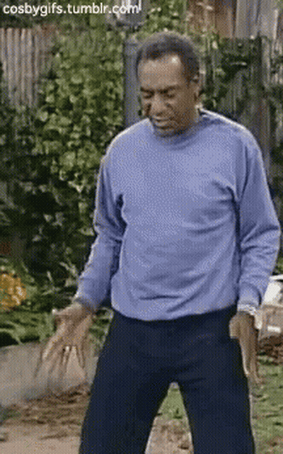 A Man In A Blue Shirt Is Dancing In Front Of A Fence . GIF