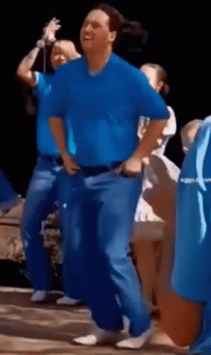 A Man In A Blue Shirt Is Dancing In Front Of A Group Of People GIF