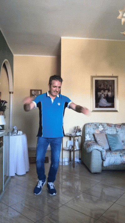 A Man In A Blue Shirt Is Dancing In Front Of A Picture Of A Bride And Groom GIF