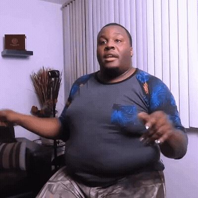 A Man In A Blue Shirt Is Dancing In Front Of A Window With Blinds GIF
