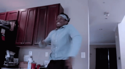 A Man In A Blue Shirt Is Dancing In The Kitchen GIF